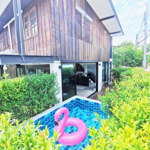 una piscina con un flamenco rosa frente a una casa en Stay Here Hostel en Chiang Mai