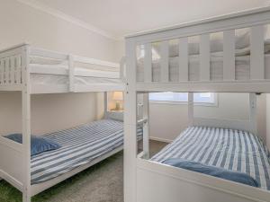 two white bunk beds in a room with a bed at All Decked Out in Smiths Beach