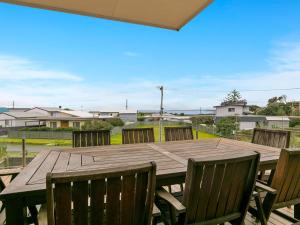 a wooden table and chairs on a patio at Swan Bay Views in Surf Beach