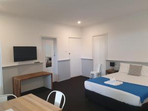 a bedroom with a bed and a table and a tv at Squid's Ink Motel in Belmont