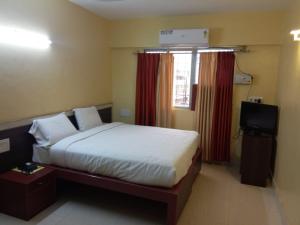 a bedroom with a bed and a television in it at Hotel Vyshak International in Mysore
