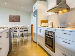 une cuisine avec des placards blancs et une salle à manger avec une table dans l'établissement Beach Retreat on Koala, à Cowes