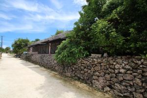 a stone retaining wall next to a building at Taketomijima Guesthouse and je Taime in Taketomi