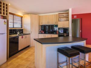 a kitchen with a bar with two stools in it at Blue Haven in Cape Woolamai