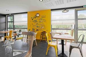 a restaurant with tables and chairs and yellow walls at Campanile Roissy - Aéroport CDG - Le Mesnil Amelot in Le Mesnil-Amelot