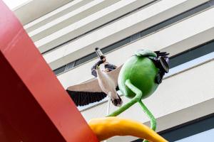 a green bird is hanging from a building at Volkshotel in Amsterdam