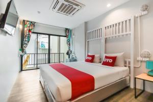 1 dormitorio con 1 cama grande con almohadas rojas en OYO 1074 Fin Hostel, en Kata Beach