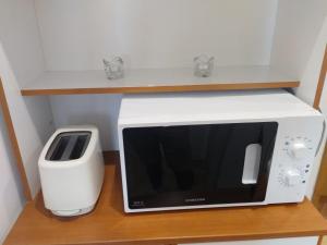 a microwave and a toaster on a wooden shelf at Ultracentral Apartments in Bucharest