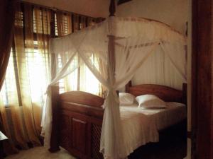 a bedroom with a canopy bed with white curtains at Tea Hills Bungalow in Hatton