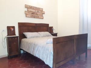 1 cama con cabecero de madera y un cartel en la pared en B&B La Locanda en Fiuggi