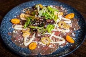 un plato azul de comida con verduras y carne en Prins Hendrik Texel en Oost