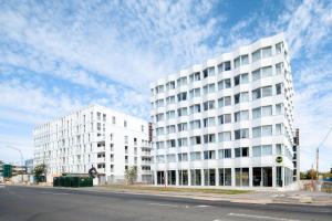 dos edificios blancos en una calle de la ciudad con un cielo nublado en B&B HOTEL Massy Gare TGV en Massy