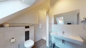 a white bathroom with a sink and a toilet at WH Hotels Papenburg Zentrum in Papenburg