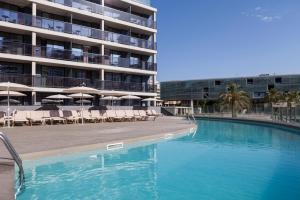 basen z krzesłami i parasolami obok budynku w obiekcie Hotel Bristol 4 Sup w mieście Benidorm
