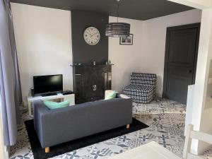 a living room with a couch and a tv and a clock at L'appart promenade de 4 heures in Spa