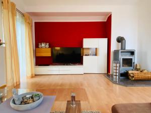 a living room with a red wall and a fireplace at Ferienwohnung Bellissima in Ering