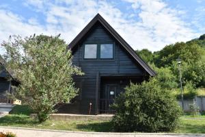 a black house with a window and a tree at Aparthotel Koliba in Nik&scaron;ić