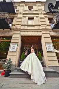a woman in a wedding dress standing in front of a building at Hotel King David The Builder in Kutaisi