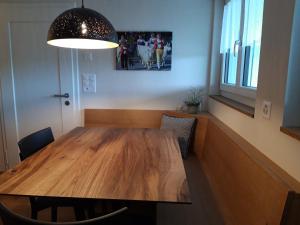 a dining room with a wooden table and a light at Appartement Säntisblüte in Rehetobel