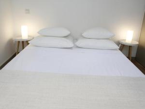 1 cama con 2 almohadas blancas y 2 mesas en Le relais de la maison Bacou, en Carcassonne