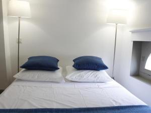 a bed with two blue pillows on top of it at Le relais de la maison Bacou in Carcassonne +3 photos