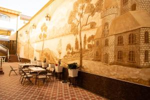 Cinzano Complex في سمرقند: لوحة جدارية على جانب مبنى به طاولات وكراسي