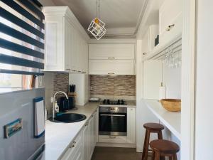 a kitchen with white cabinets and a sink and two stools at Rivera Apartments - Premium Accomodation in Iaşi