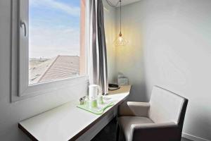 a room with a desk and a chair and a window at Campanile Roissy - Aéroport CDG - Le Mesnil Amelot in Le Mesnil-Amelot