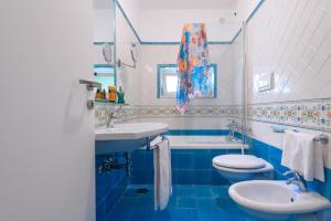 a blue and white bathroom with two toilets and a sink at Amalfi Suite Boutique Hotel in Amalfi