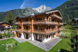 una grande casa in legno con montagne sullo sfondo di Coin des Drus Apartment - Chamonix All Year a Chamonix-Mont-Blanc