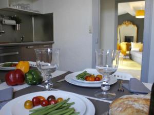 una mesa con platos de verduras y vasos. en Maison Bacou N2, en Carcassonne