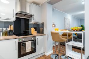 a kitchen with white cabinets and a table with a bowl of fruit at Large Apartment Near Stonehenge Amesbury Town Centre Smart TVs Netflix FREE PARKING in Amesbury +10 photos