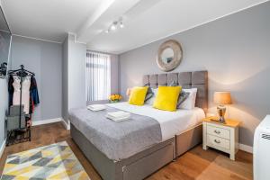 a bedroom with a bed with yellow pillows and a mirror at Large Apartment Near Stonehenge Amesbury Town Centre Smart TVs Netflix FREE PARKING in Amesbury