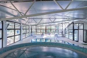 an indoor swimming pool in a building with windows at Hotel Flores in Poreč