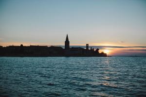 an island in the water with a clock tower at sunset at Hotel Flores in Poreč