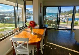 uma sala de jantar com uma mesa de madeira e cadeiras brancas em Vista Marina Penthouse #5 - Amazing views & location em Bermagui