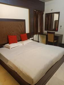 ein Schlafzimmer mit einem großen Bett mit zwei roten Kissen in der Unterkunft Hotel V.I.P. Regency in Dhanbad