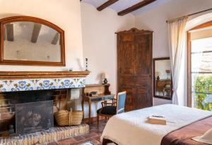 1 dormitorio con chimenea, 1 cama y espejo en El Palauet de Monells - Adults Only, en Monells