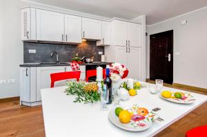 a white kitchen with a table with fruit on it at Nel Centro City Apartment in Rovinj