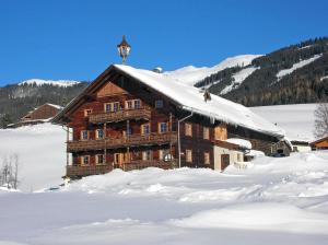 ein großes Holzgebäude mit Schnee auf dem Boden in der Unterkunft Almliesl MITT-396 in Mittersill