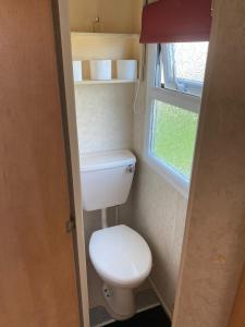 a small bathroom with a toilet and a window at Eastgate Fantasy Islands Static Caravan Park in Ingoldmells