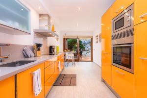 cocina con armarios de color naranja y fregadero en S Arbosera, en Font de Sa Cala
