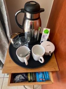 a table with a tea pot and two cups on a plate at Bonzila in Pretoria