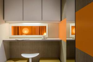 a kitchen with a counter with a stool and a window at AppartHotel Mercure Paris Boulogne in Boulogne-Billancourt