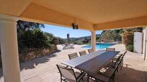 a wooden table and chairs on a patio with a pool at Villa Alinea in Sainte-Maxime
