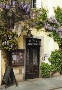 a building with a sign and purple flowers on it at Penzion Kamenne Slunce in Telč