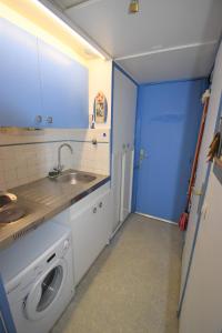 eine Küche mit einer Waschmaschine und einer blauen Tür in der Unterkunft les jardins du port studio avec jardin et piscine in Le Grau-du-Roi