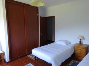 a bedroom with a white bed and a wooden closet at Hospedaria Lampião in Penacova