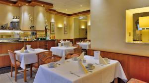 a restaurant with white tables and chairs and a kitchen at Hotel Ilbertz in Cologne