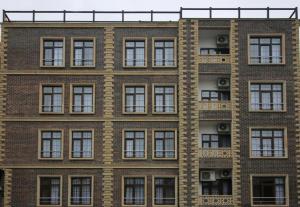 バクーにあるTour-ZamZam-Madinah Halal Hotels Groupの窓とエアコンが備わる高いレンガ造りの建物です。